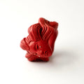 Ghost ring - red variant - on a white surface on its side with sculpted details clearly visible