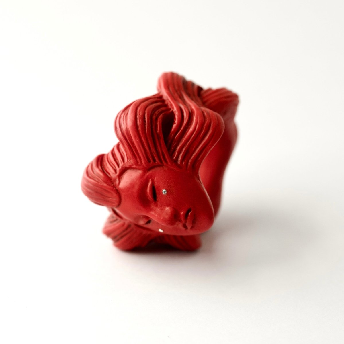 Ghost ring - red variant - on a white surface on its side with sculpted details clearly visible