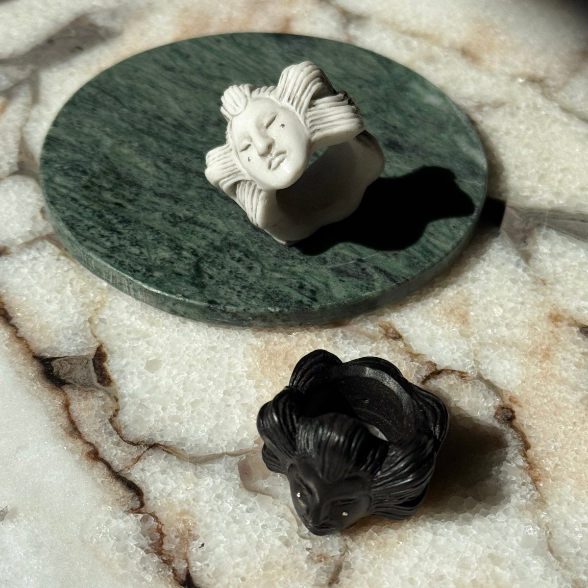 Ghost ring - black and white variants, on a light marble surface, lifestyle editorial
