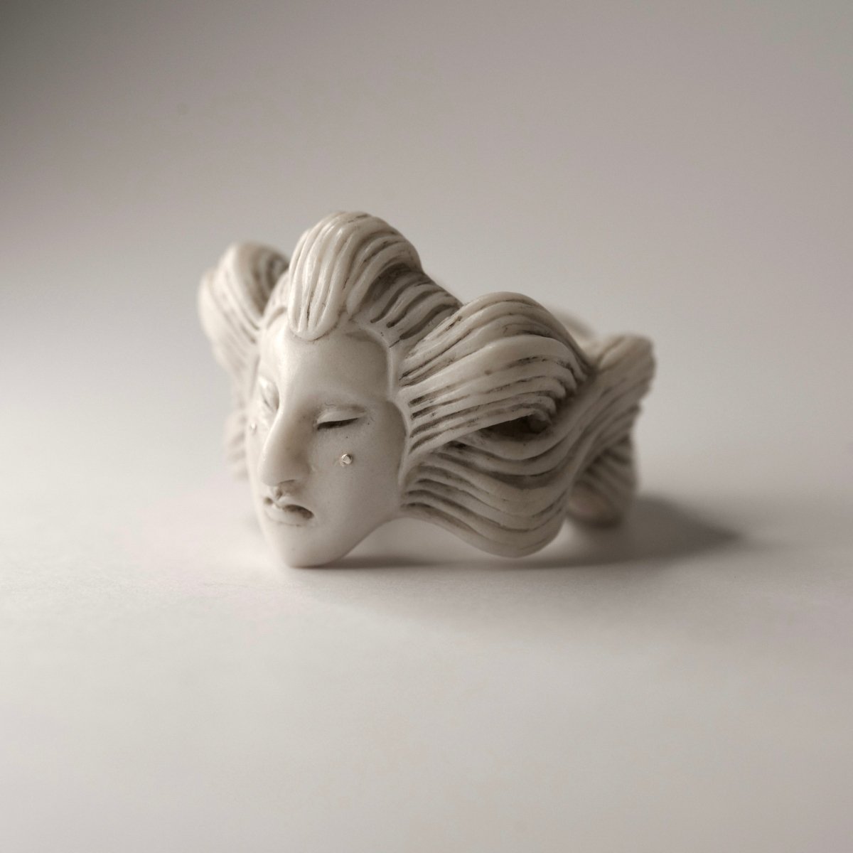 Ghost ring - white variant - placed on a white surface, focus on sterling silver details
