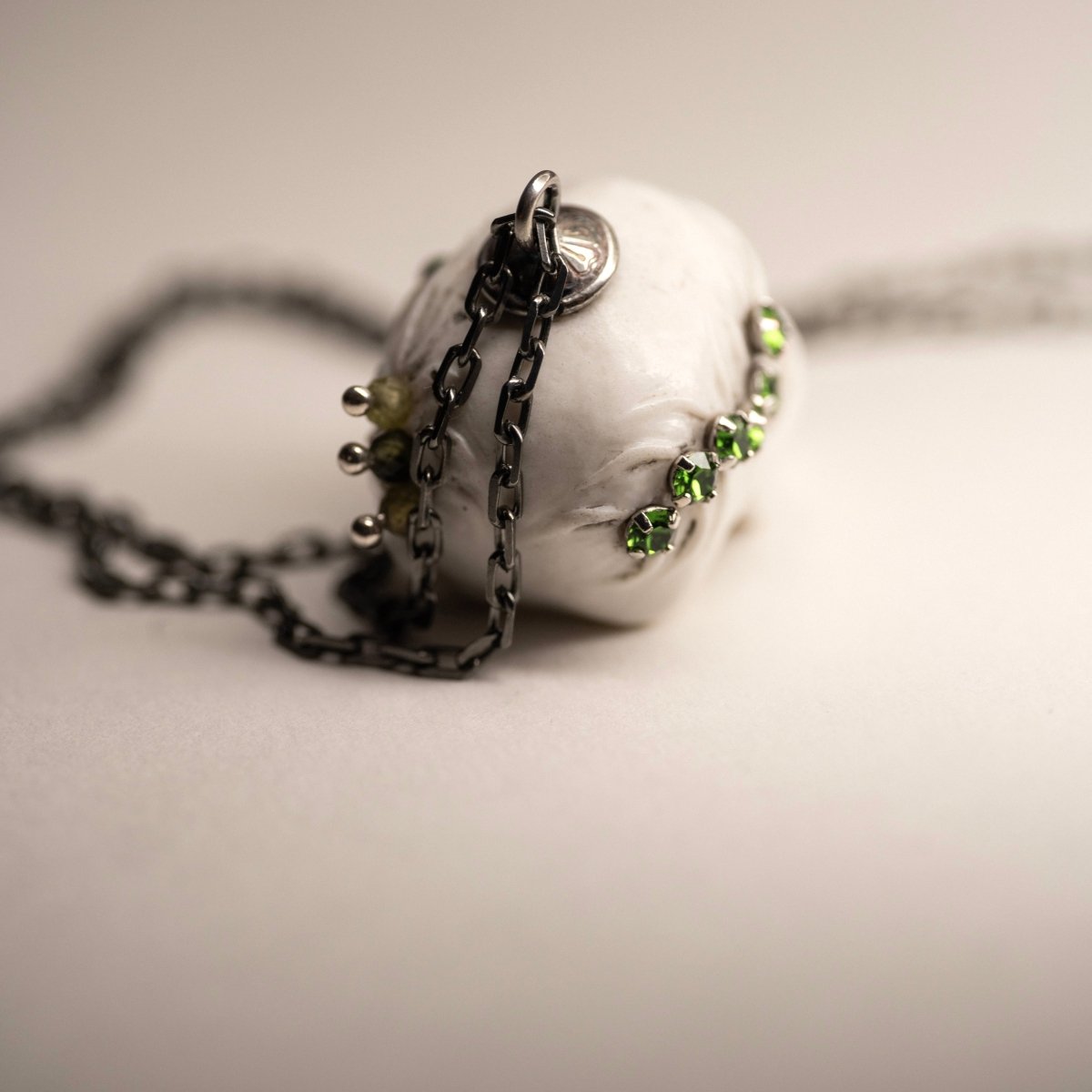 Beetles Skull pendant back part view, with focus on chain fixture and various green gems