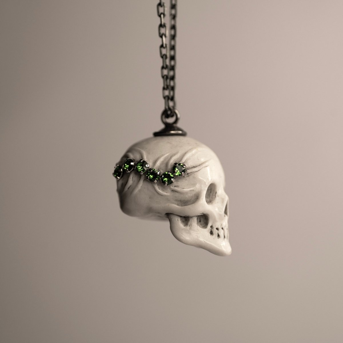 Beetles Skull pendant placed against white background, green gems-bejewelled scolopendra visible on the side of the skull pendant