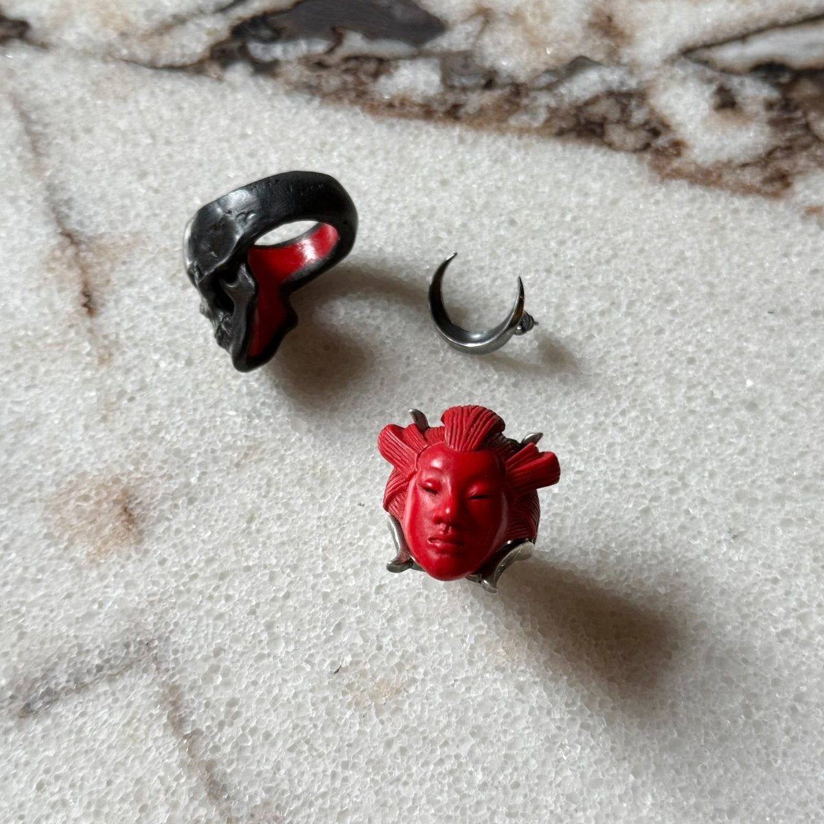 She ring, Luna earring and Lacquer Skull ring are placed on white marble surface