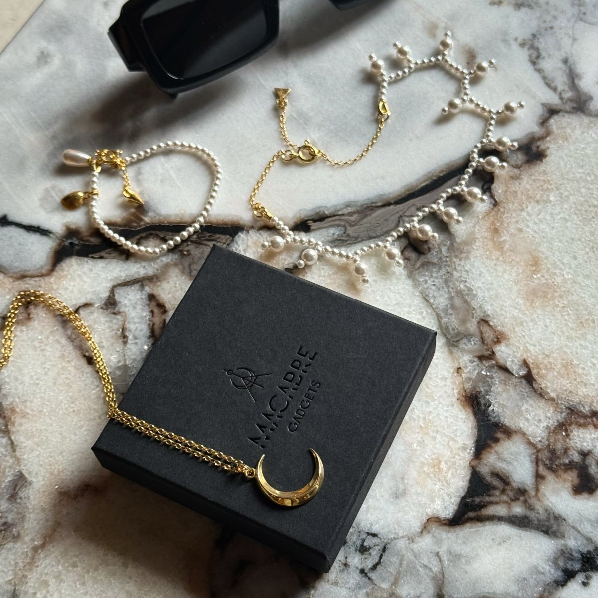Luna pendant by Macabre Gadgets placed on a branded box, along with Sacred Pearls  necklace and Pearl bracelet