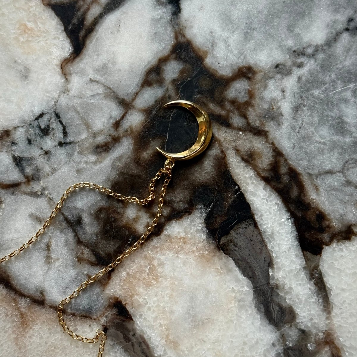 Luna pendant by Macabre Gadgets - gold variant, placed on marble surface