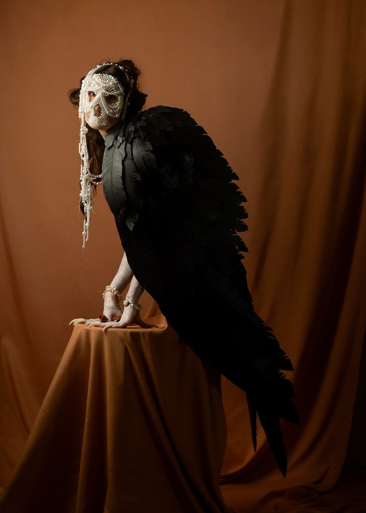 Full figure of the mythological Siren, a giant black bird with a human head, seated on a pedestal, Gods and Monsters THEA campaign | Macabre Gadgets
