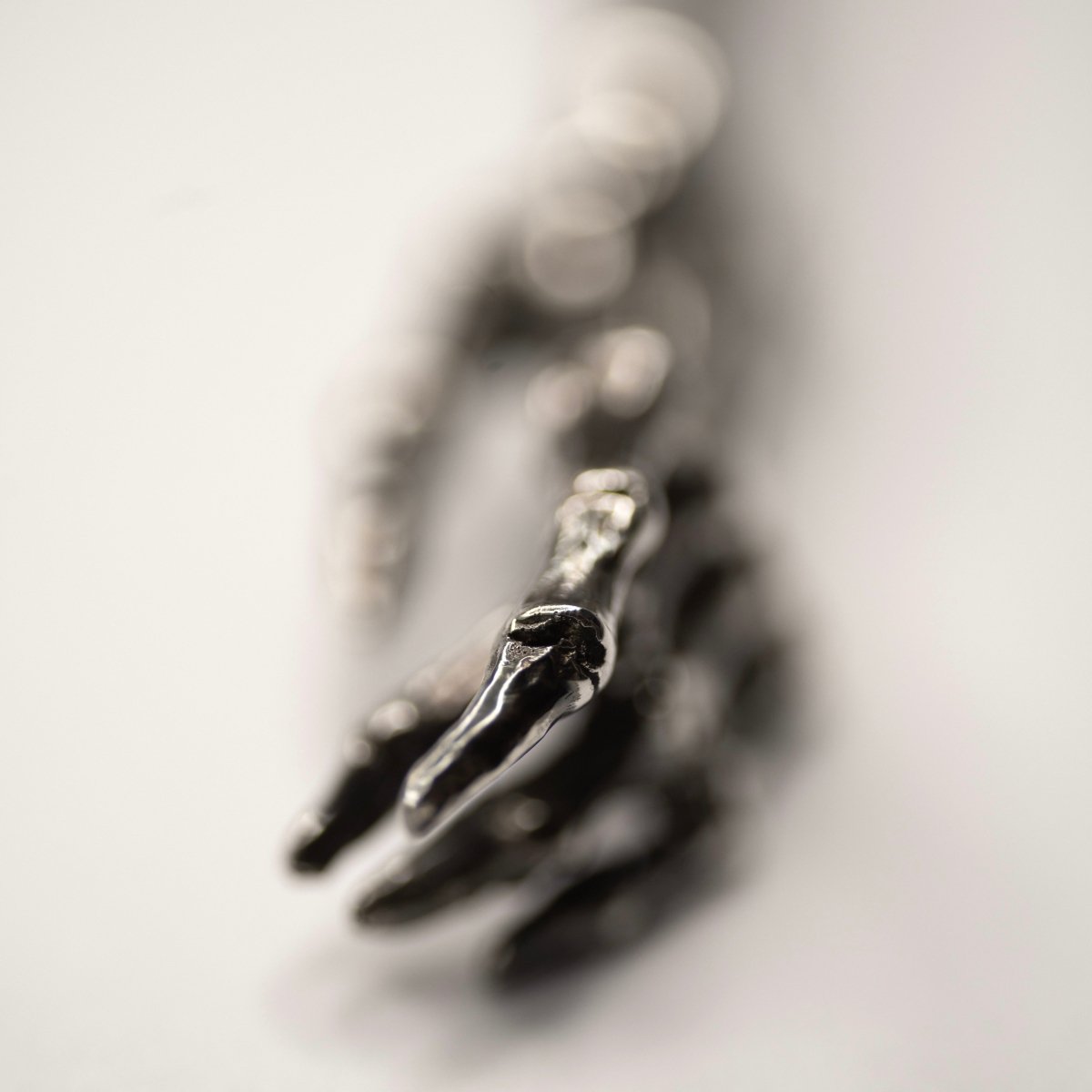 Silver Skeleton Arm pendant - artistic picture with focus on fingertips and the rest of the pendant is blurry