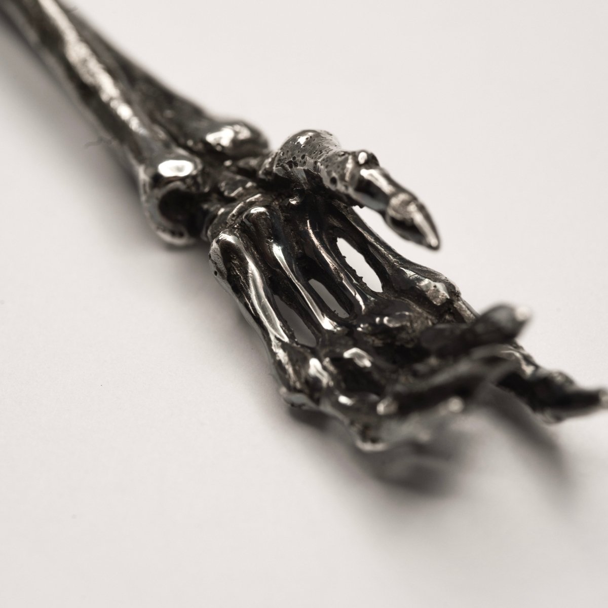 Silver Skeleton Arm pendant close up on a hand part with fingers and joints visible