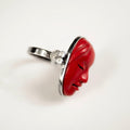 Mask ring - red variant - placed on a white surface on its a side, with mask relief details and ring silver decoration visible