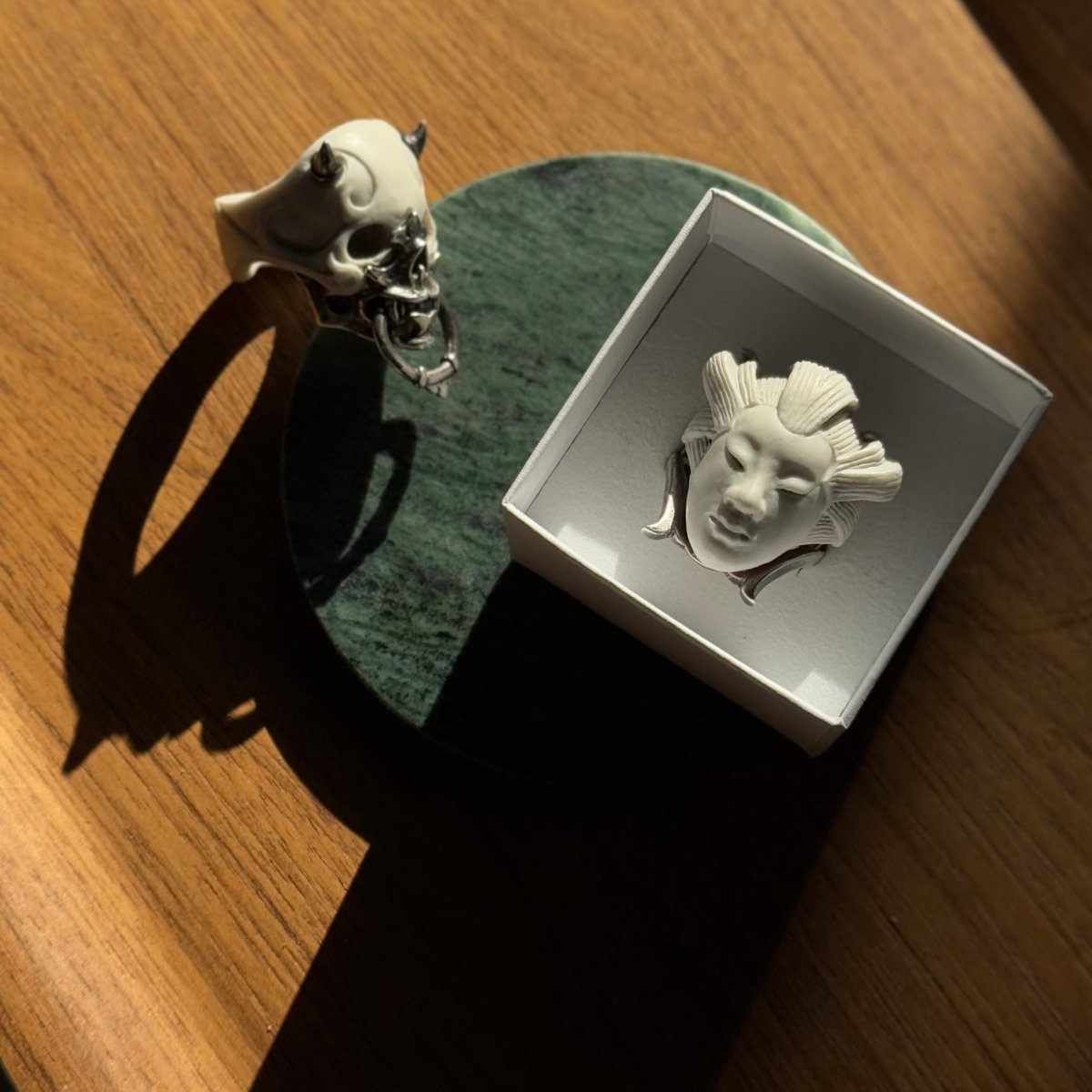 Masked Skull ring and She ring on a wooden surface under sunset light — lifestyle editorial, DREAMS collection
