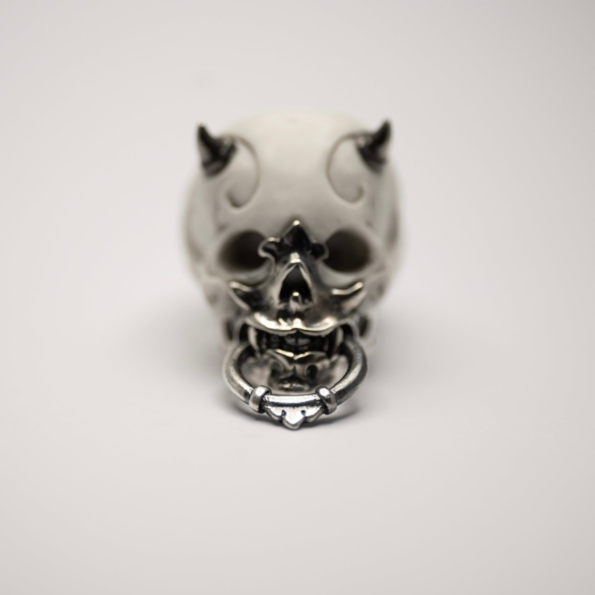 Masked Skull ring — white marble variant — front view showing sterling silver jaw-mask, ornamental marble relief and silver horns