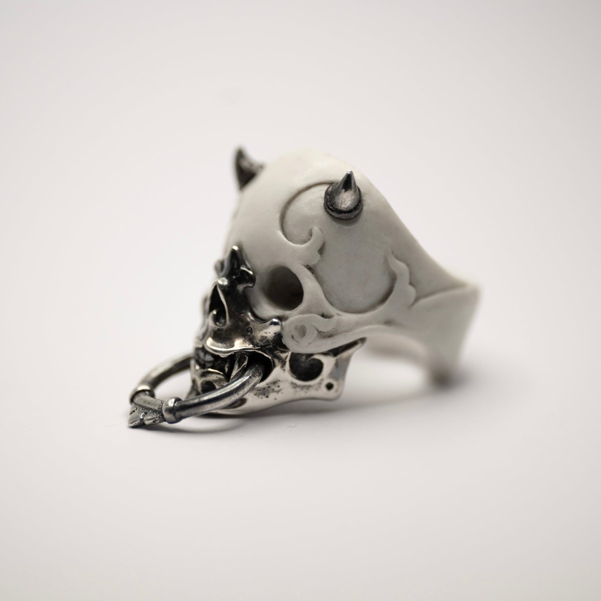 Masked Skull ring — white marble variant — semi-side view showing ornamental relief on marble skull and sterling silver surfaces