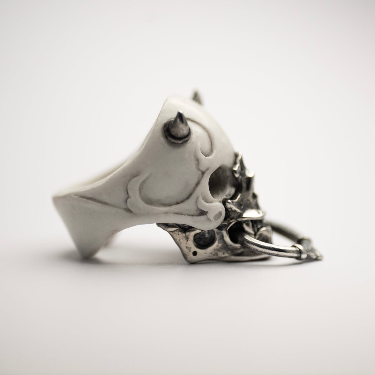 Masked Skull ring — white marble variant — side view with silver horns, ornamental hoop and jaw-mask clearly visible