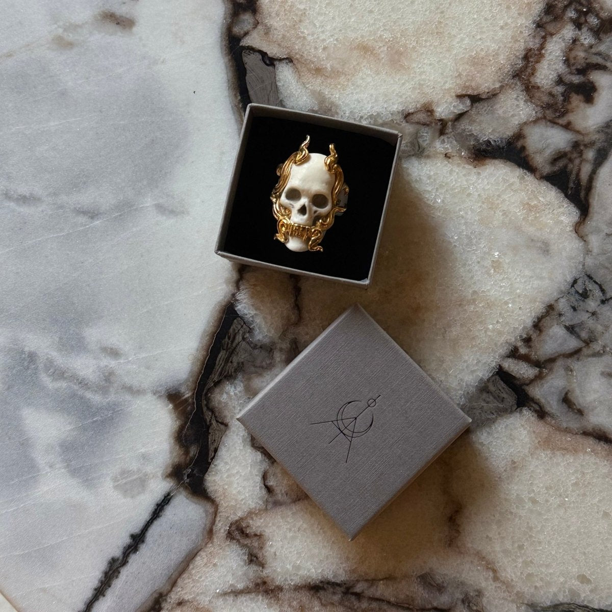 Mayla Skull ring in a jewelry box placed on a white marble surface
