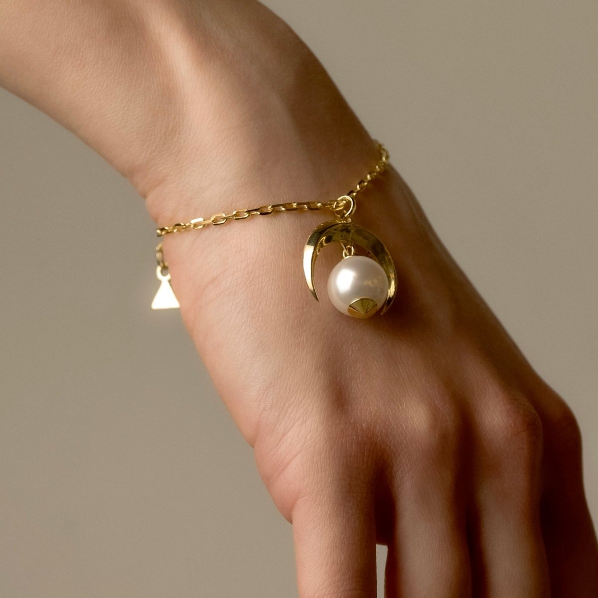 Moon bracelet - gold variant - on a model's hand, moon and pearl detail are visible