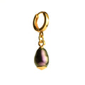 Olive Pearl earring placed against white surface, huggie and pearl clearly visible