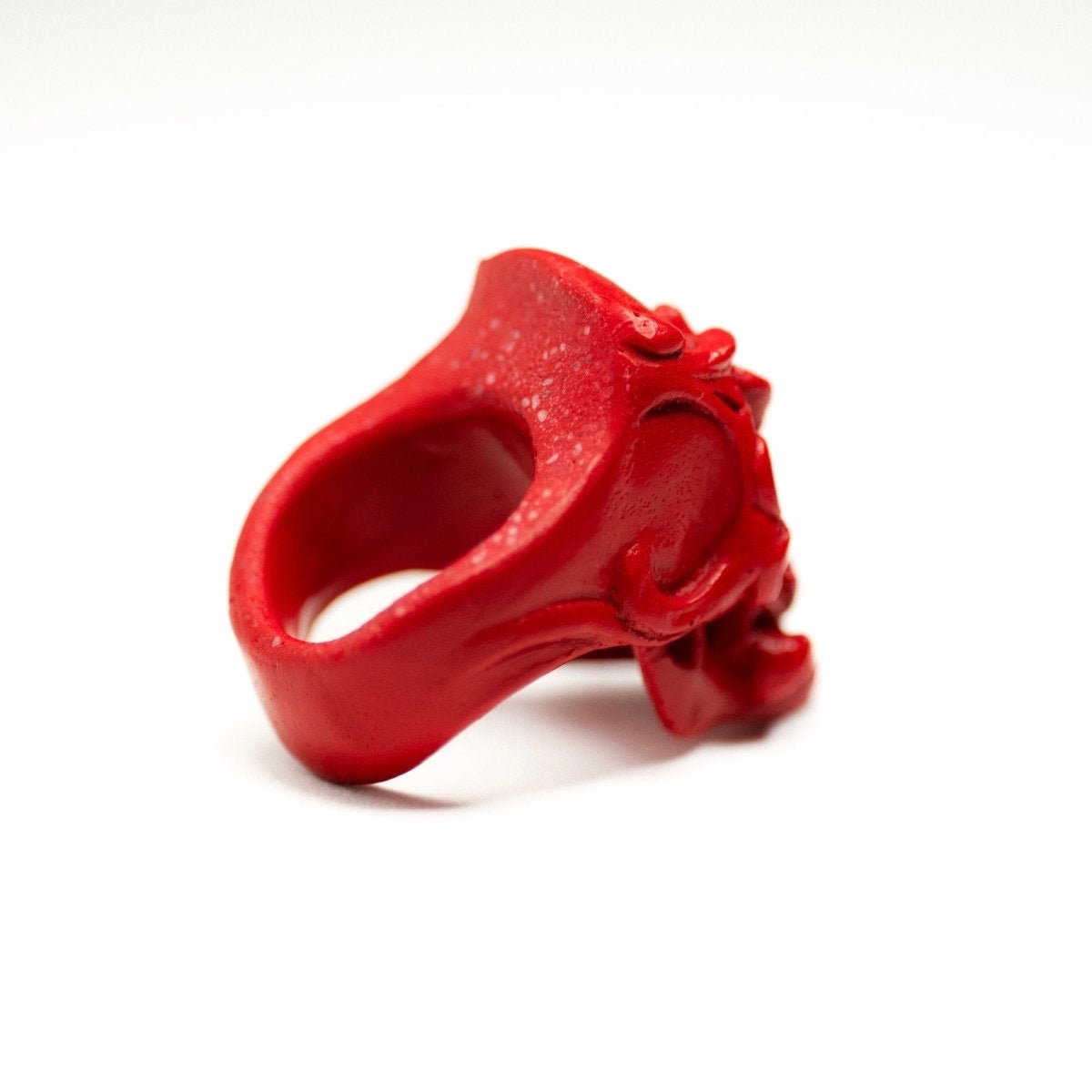 Orchid Skull ring red variant on white surface, back side of the ring visible