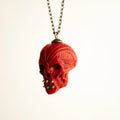 Ornate Skull pendant against white background, semi-profile view, sterling silver decoration and chain are clearly visible