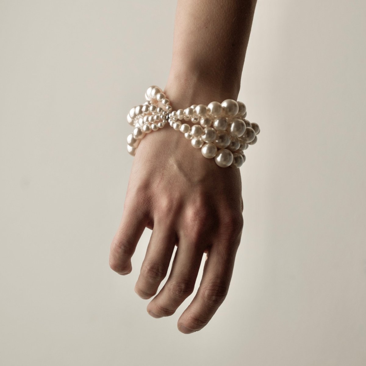 Multi-strand Pearl bracelet on a female's wrist - focus on tangled pearls strings and overall poetic image of the bracelet