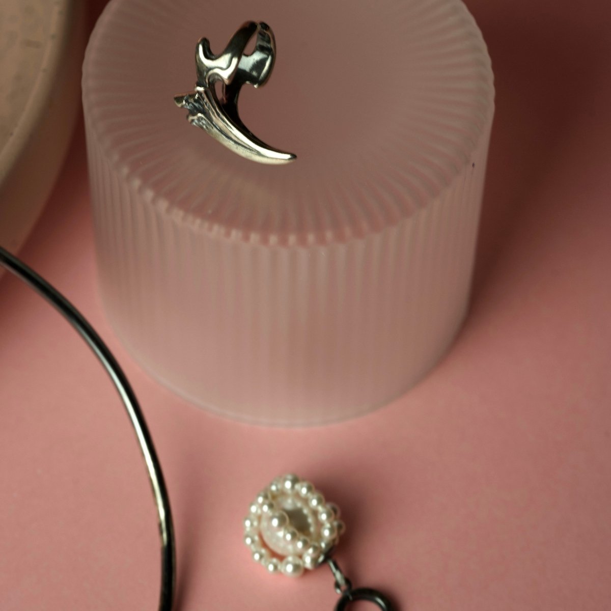 Pearl Cloud earring  and Claw phalanx ring on a pink surface, lifestyle editorial