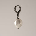 Pearl Coin earring with large glass pearl suspended from sterling silver hoop on neutral background, handcrafted jewelry detail