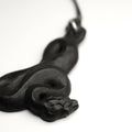 Serpent necklace - close-up of snake's head on white surface