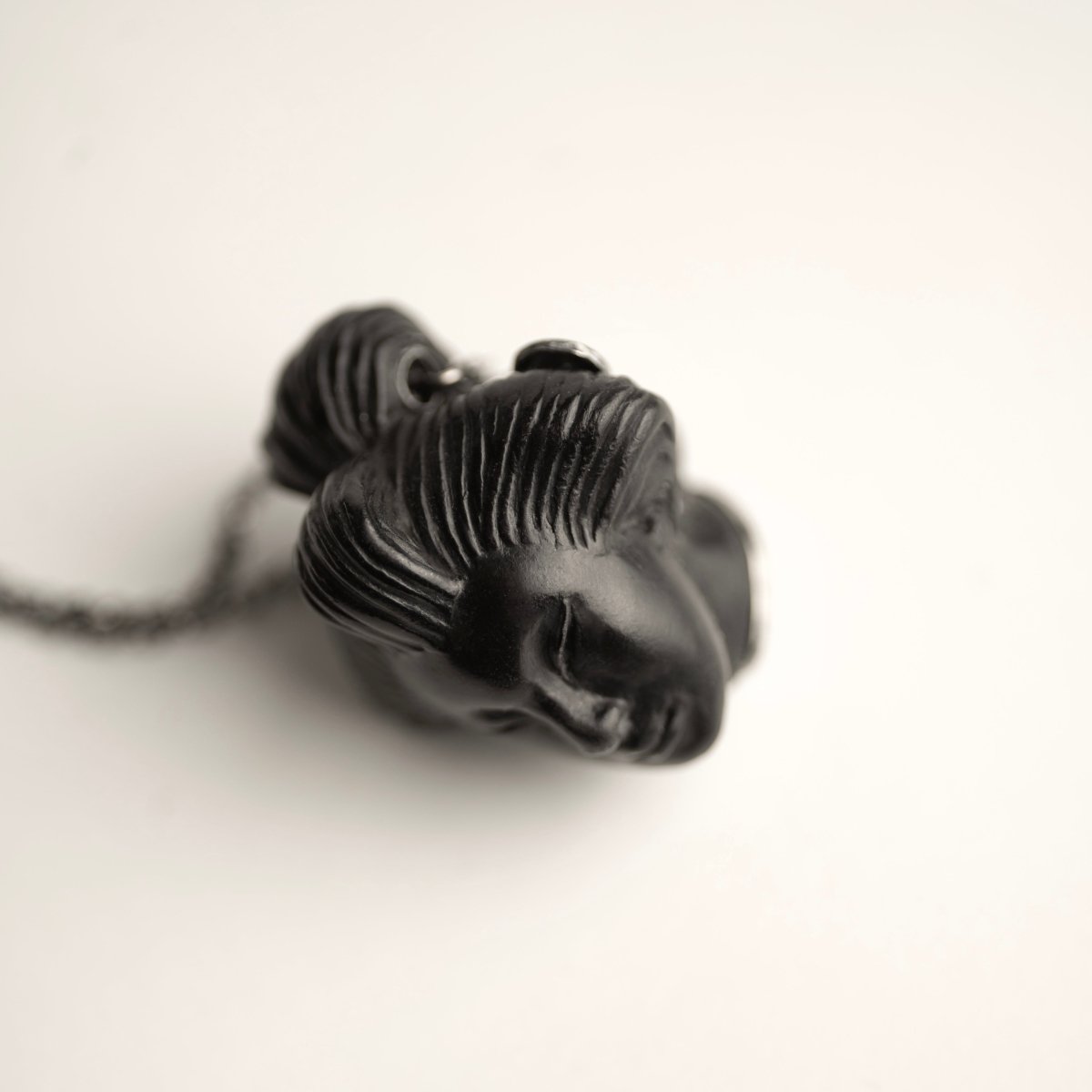 She pendant, black variant, placed on a white surface