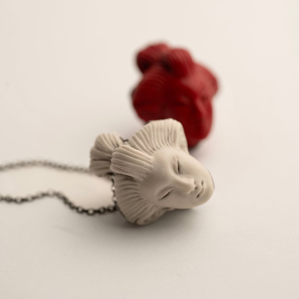 She pendant, both white and red variants, with focus on the white one, while the red is slightly blurry in the background