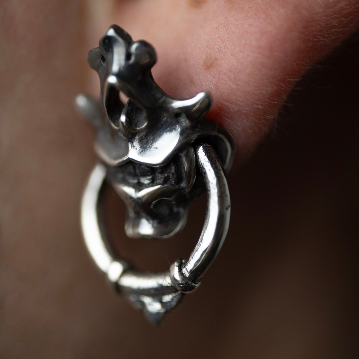 Silver Mask earring — close up on earlobe showing fit and sculptural skull mask form