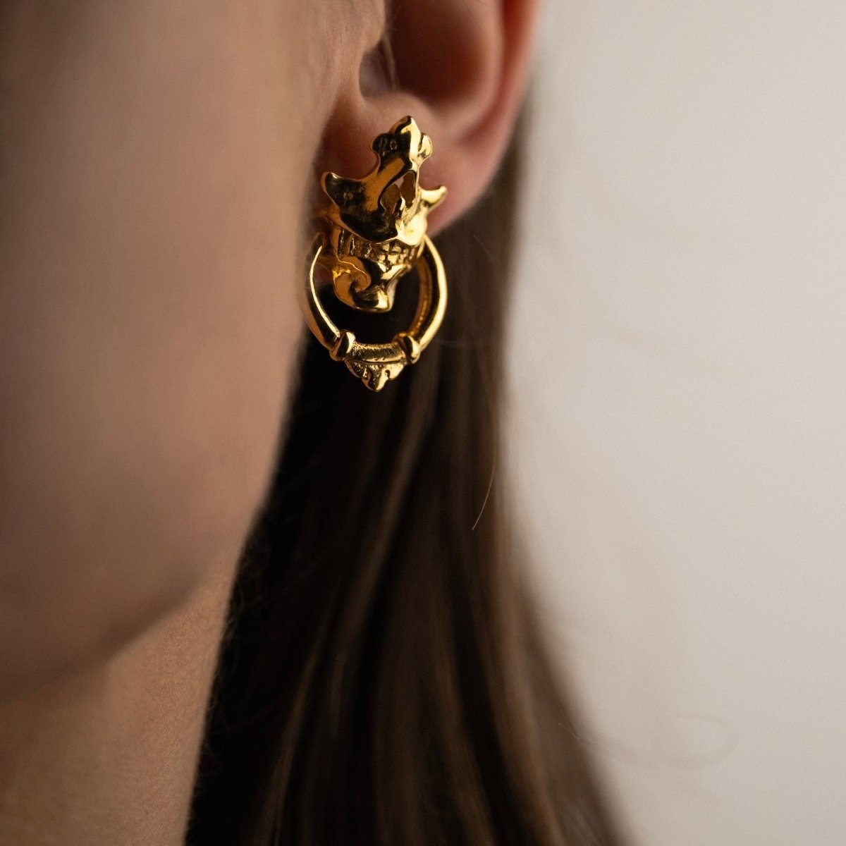 Silver Mask earring — 24K gold-plated variant — worn on a female model with long hair, showing scale and proportions