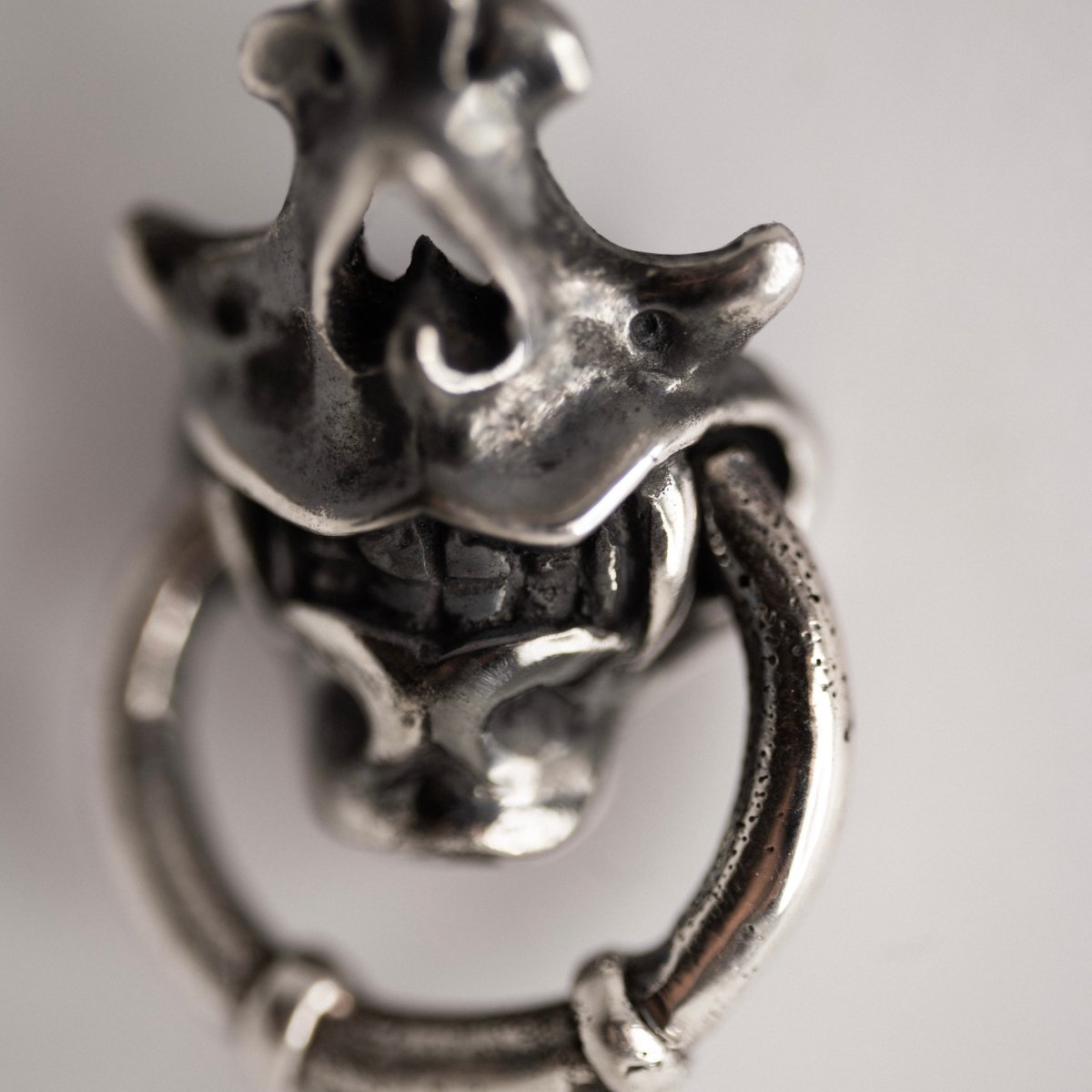Silver Mask earring — close up on ornamental surface detailing and ceremonial skull mask relief