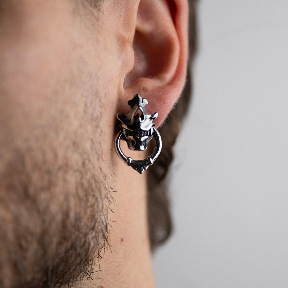 Silver Mask earring — sterling silver variant — worn on a male model with a beard, showing scale and proportions