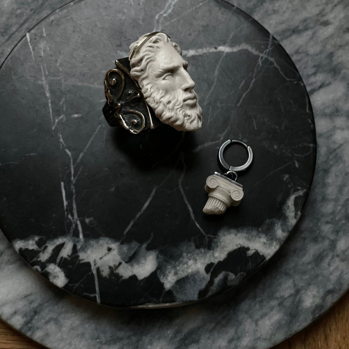 Silver Zeus ring and Ionic earring by Macabre Gadgets — greek mythology statement jewelry lifestyle shot on dark marble surface