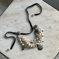 Siren Pearl Necklace - torsade necklace from pearls of different size and shape  placed on a marble table, size adjustable lace is visible