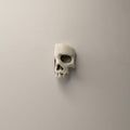 Skull Fragment earring by Macabre Gadgets, front view of a skull stud earring on a neutral background 