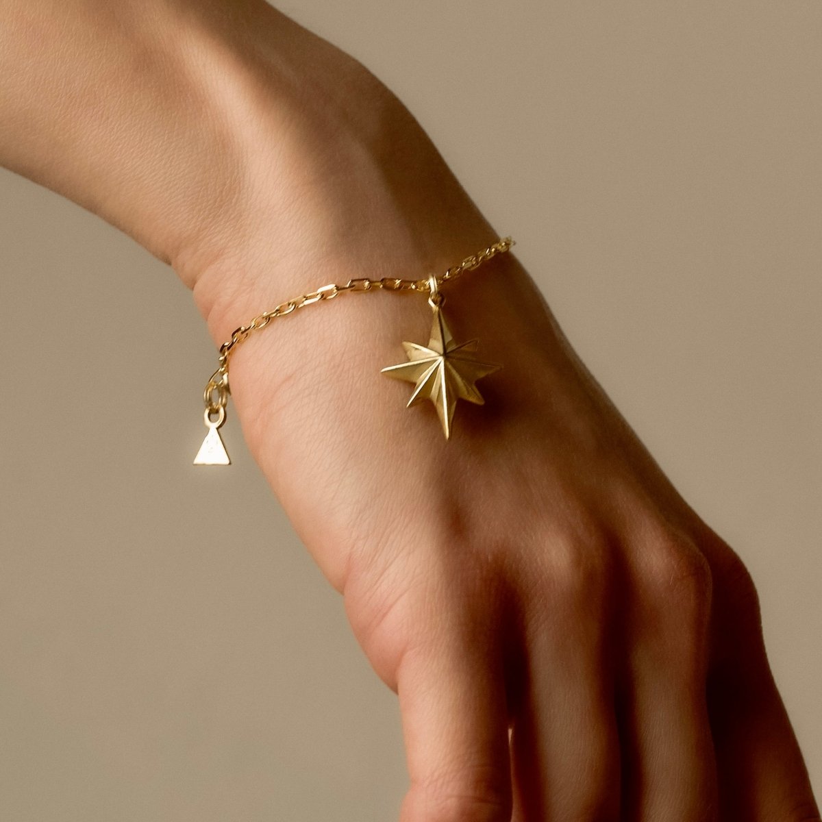 Star bracelet on a female model's hand with tanned skin, to complement the warm shine of the gold