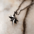 Star bracelet - silver variant - placed on a light marble surface, close up of a star detail