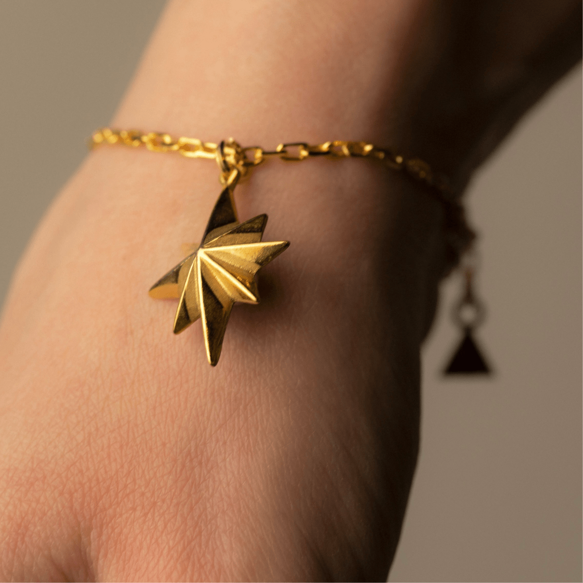 Star bracelet - gold variant - on a model's hand, close up of the star detail