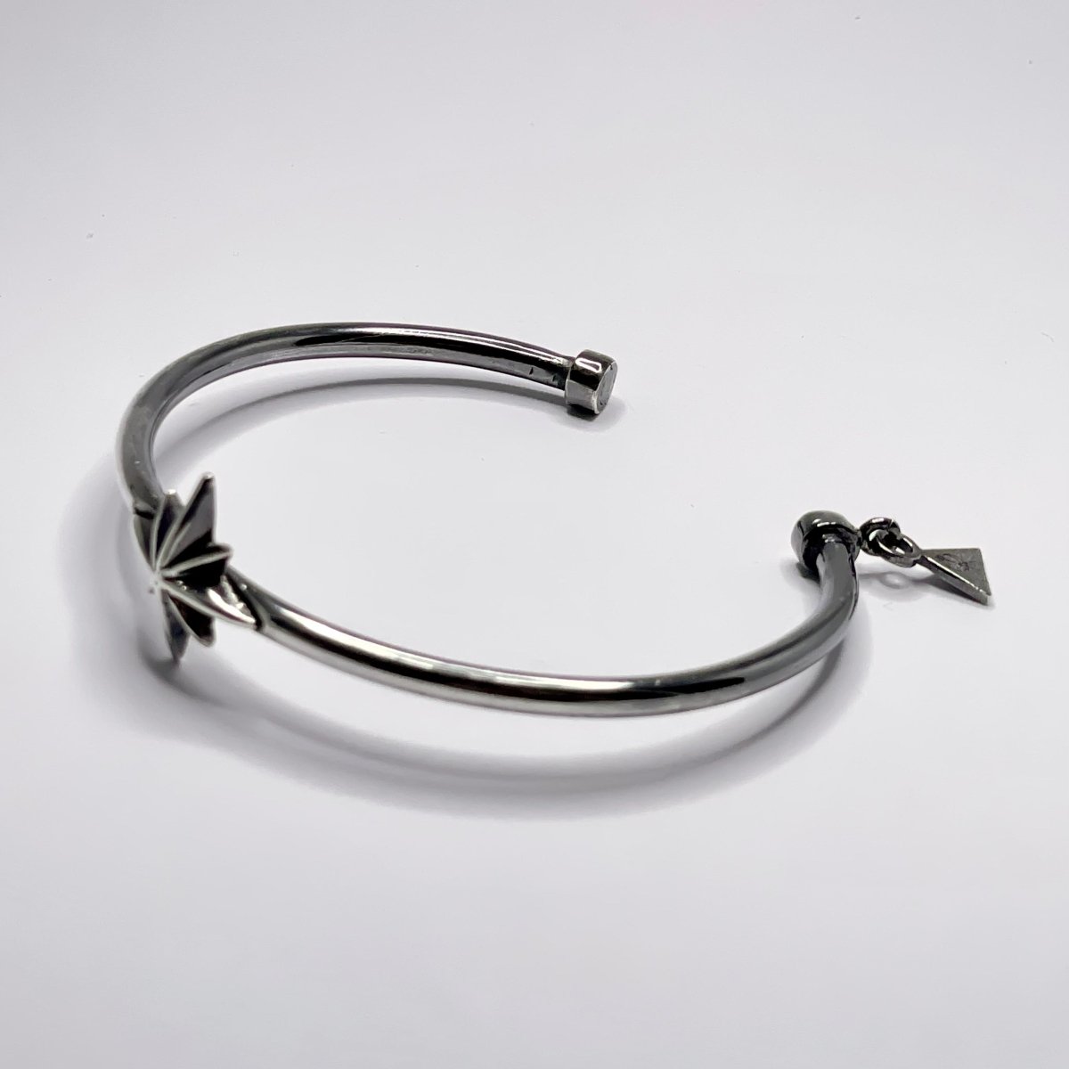 Star cuff bracelet on a white surface, clear product picture with star, logo details and opening of the bangle are clearly visible