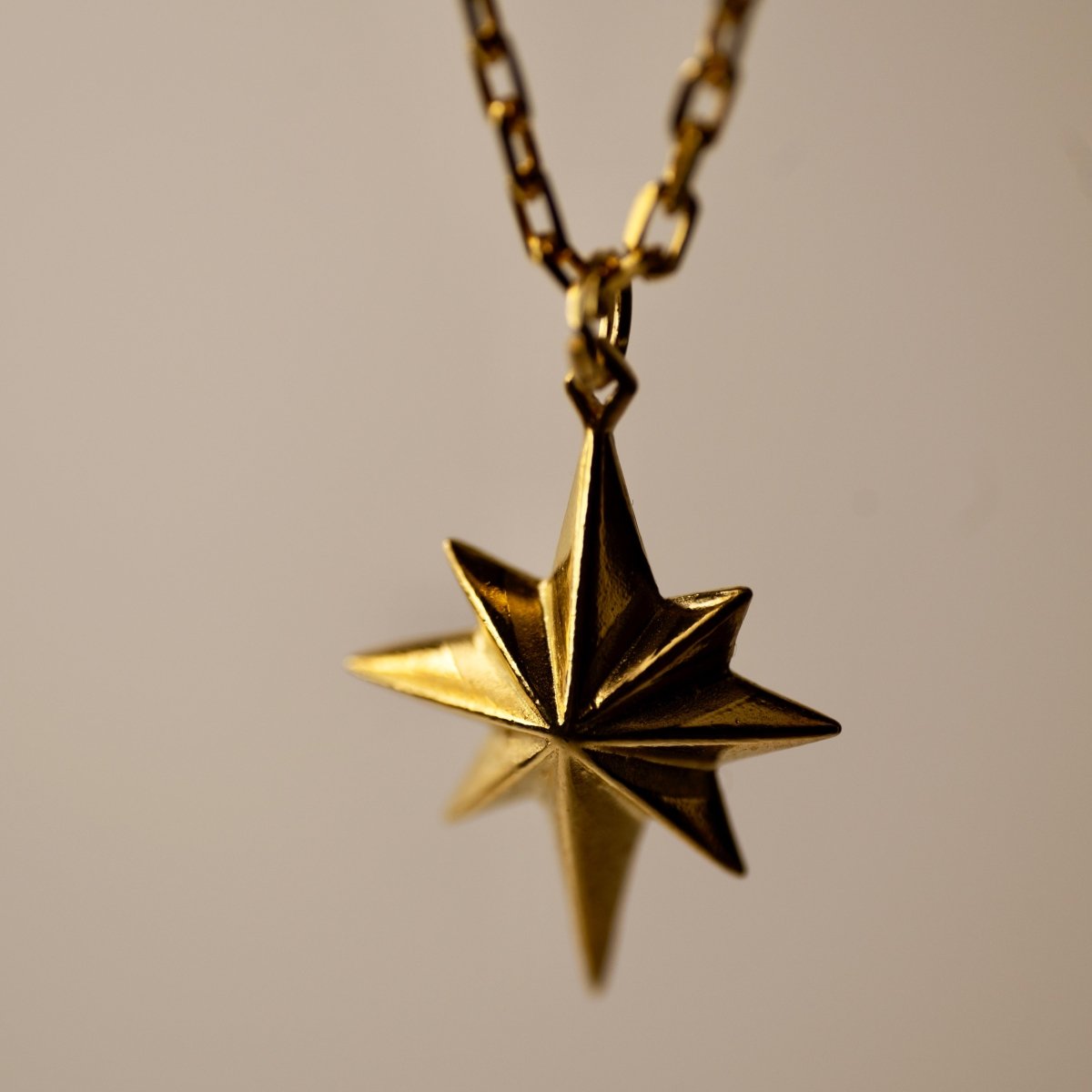 Star pendant gold — close-up of mirror-polished geometric star and chain fixture | Macabre Gadgets