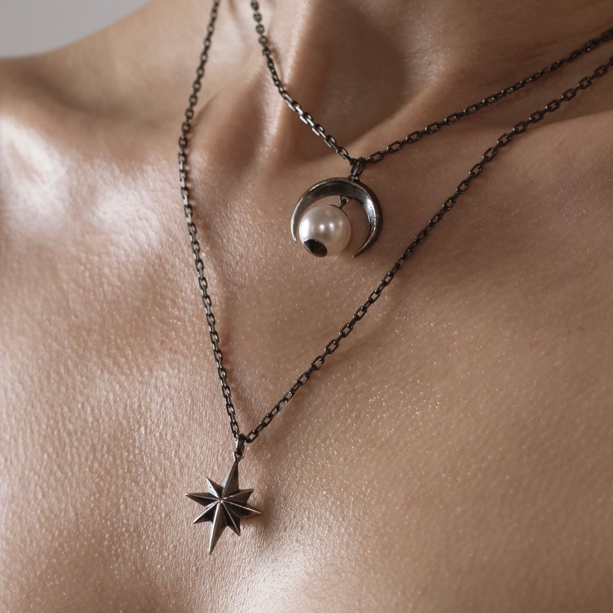 Sterling silver star pendant layered with Crescent Moon pendant on model — close-up