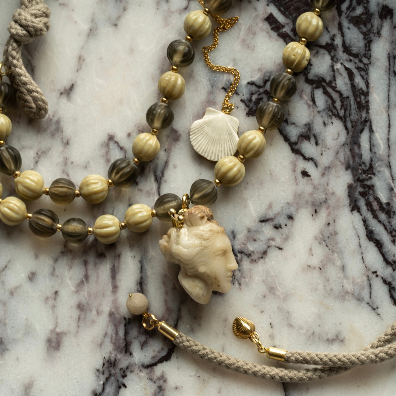Aphrsodite necklace and Shell pendant on a white marble surface