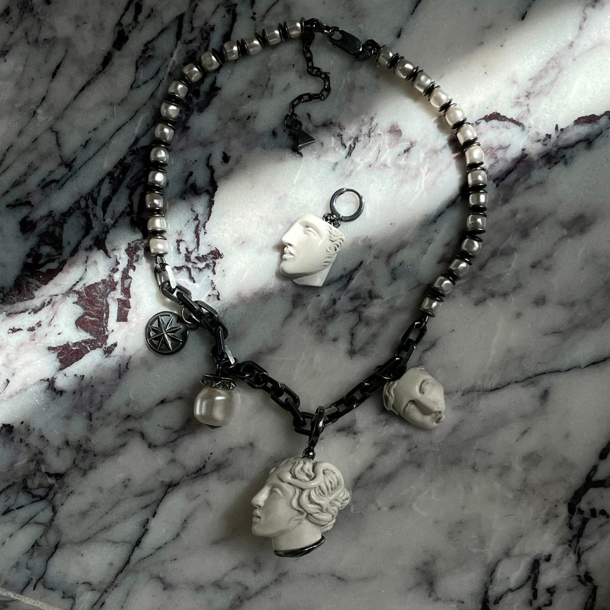 Achilles earring and Epos necklace by Macabre Gadgets on black and white marble surface