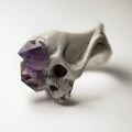 Amethyst Crystal Skull Ring on a white surface from a side,  amethyst crystals are visible 