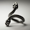 Two Headed Snake ring by Macabre Gadgets, placed on a white surface, both heads and snake skin texture are visible