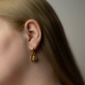 Aster earring in gold-plated finish on female model with long hair, celestial coin jewelry lifestyle shot