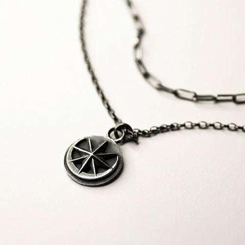 Aster coin charm on double chain, silver variant,  on neutral surface - close-up of coin shaped pendant with star and moon motif