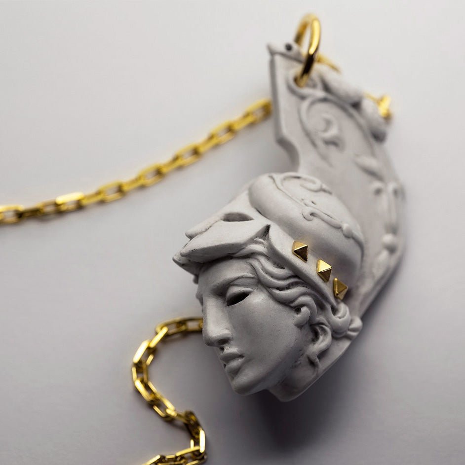 Athena pendant placed on a whiter surface with attached chain visible 