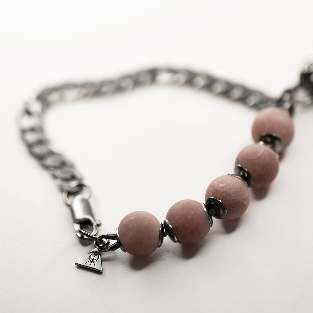 Bird Skull Bracelet placed on a white surface - close up of a miniature logo detail and rose quartz beads