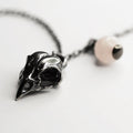 Bird skull charm-pendant placed on a white surface - close up on a charm